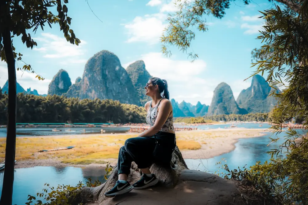 Woman sitting on rock with karst mountains background