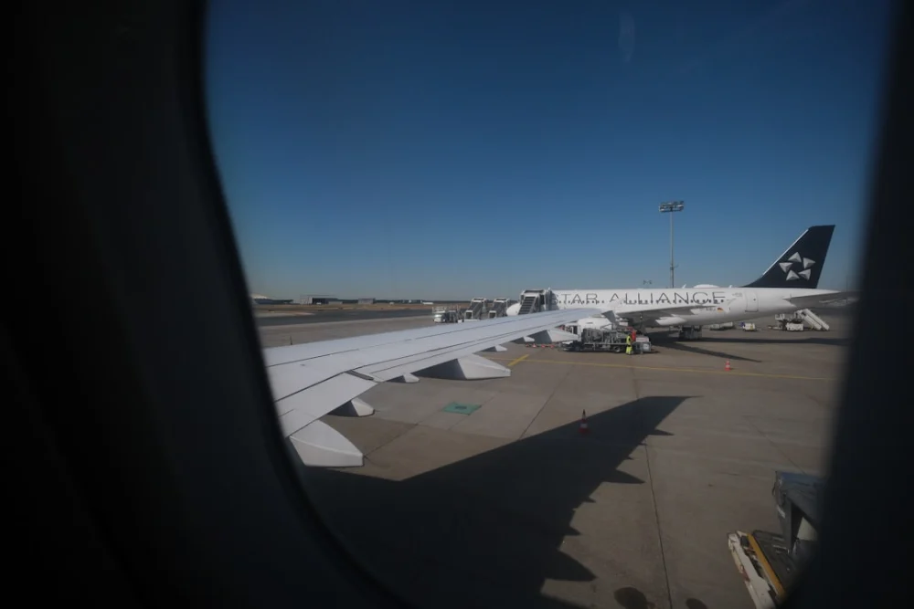 View from airplane window showing wing and parked aircraft