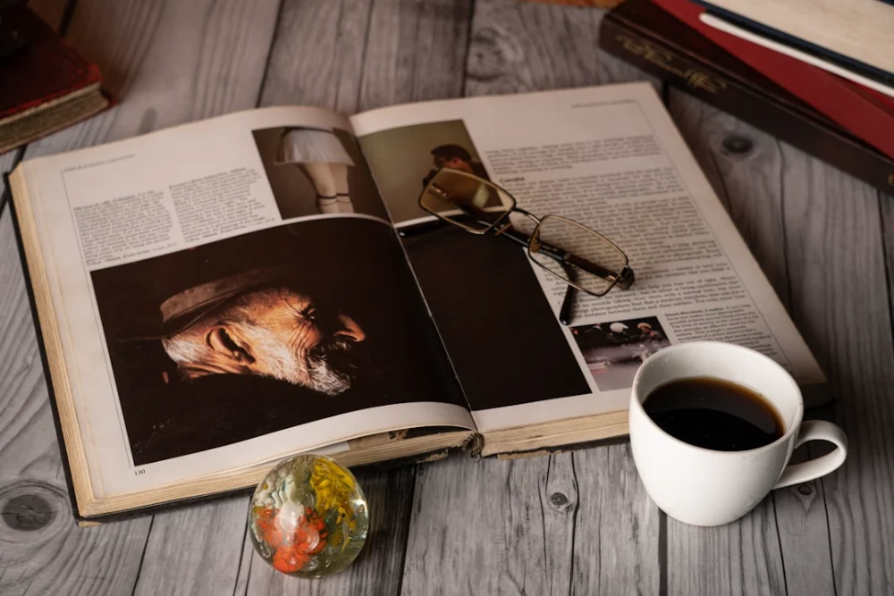 Open book with coffee and glasses on table