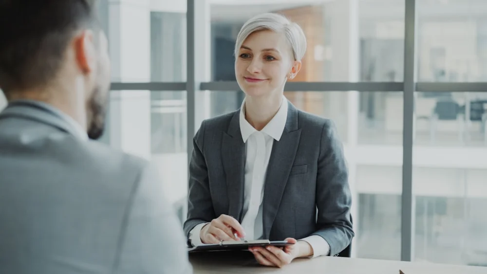 Woman in suit interviews man across table