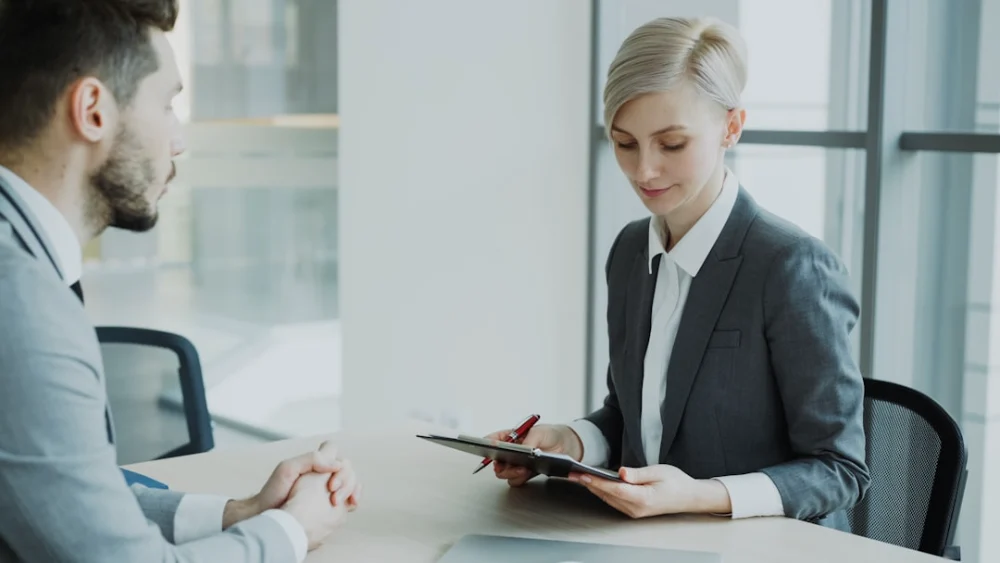 Woman in suit reviews document with man
