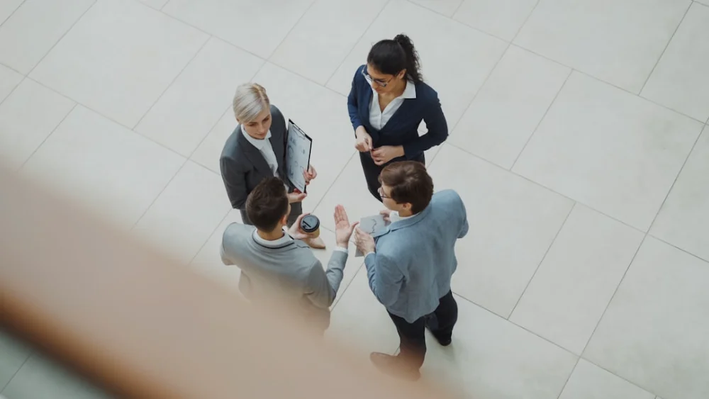 Four business people talking in a modern office lobby