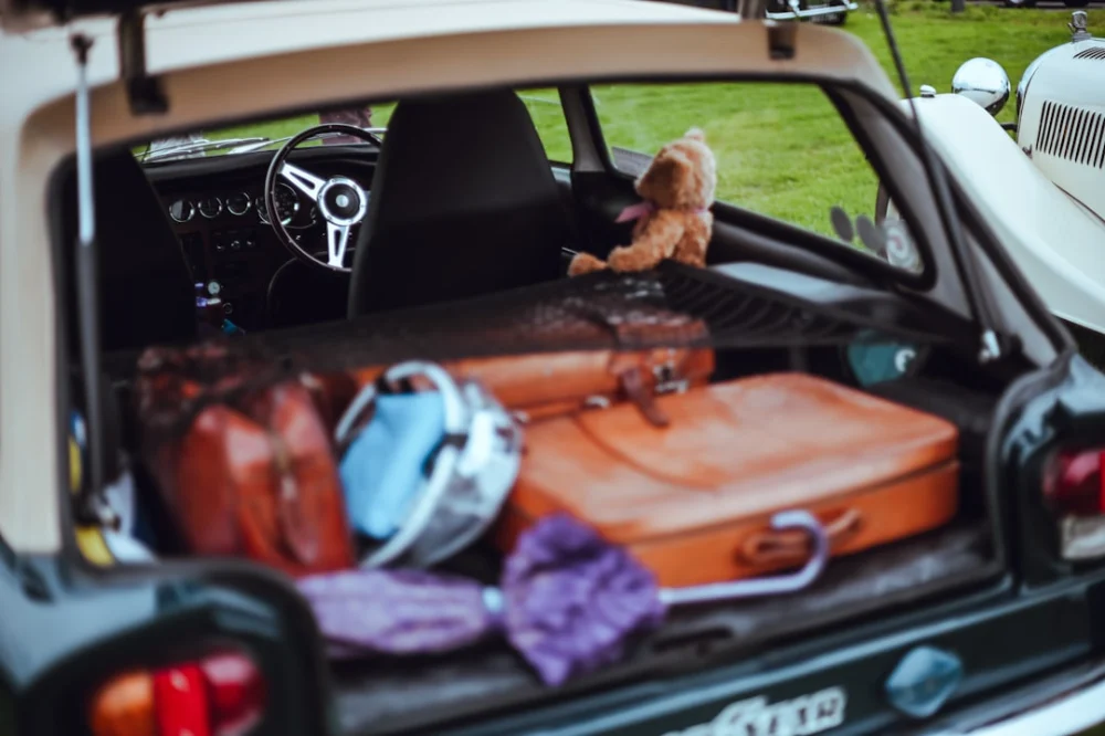 Open car trunk filled with luggage and teddy bear