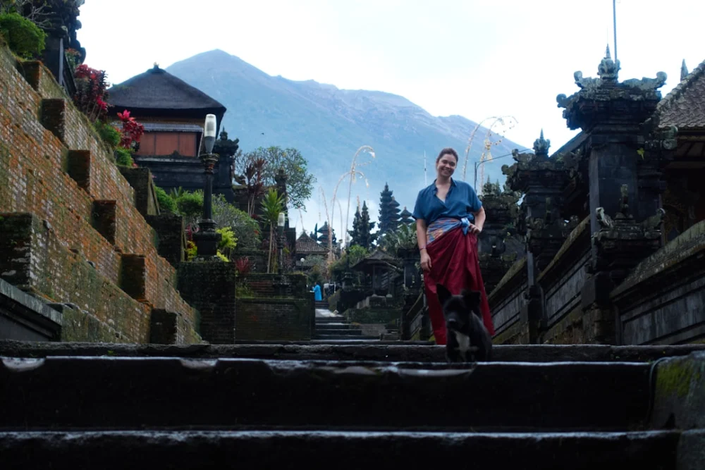 Woman in traditional clothing on temple stairs with mountain background