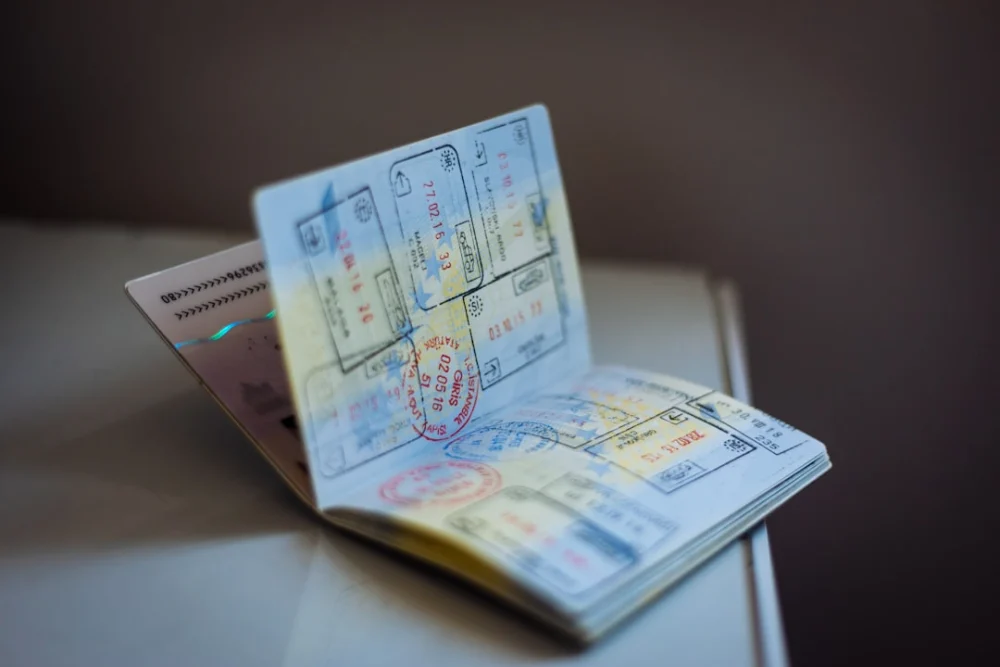 An open passport with numerous ink stamps on the pages on a table