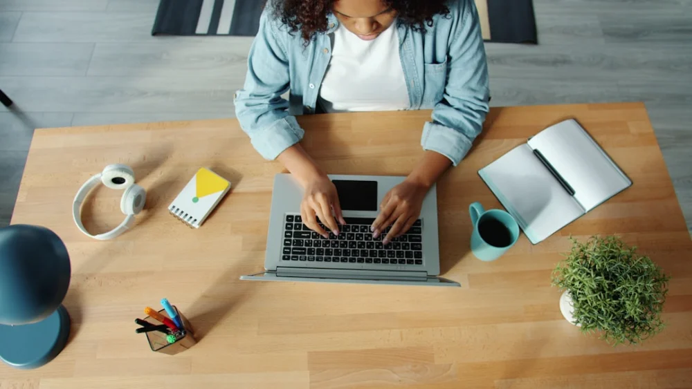 Woman typing on laptop at a wooden desk