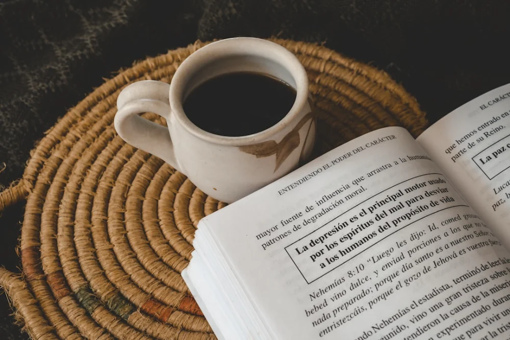 Coffee sits next to an open book
