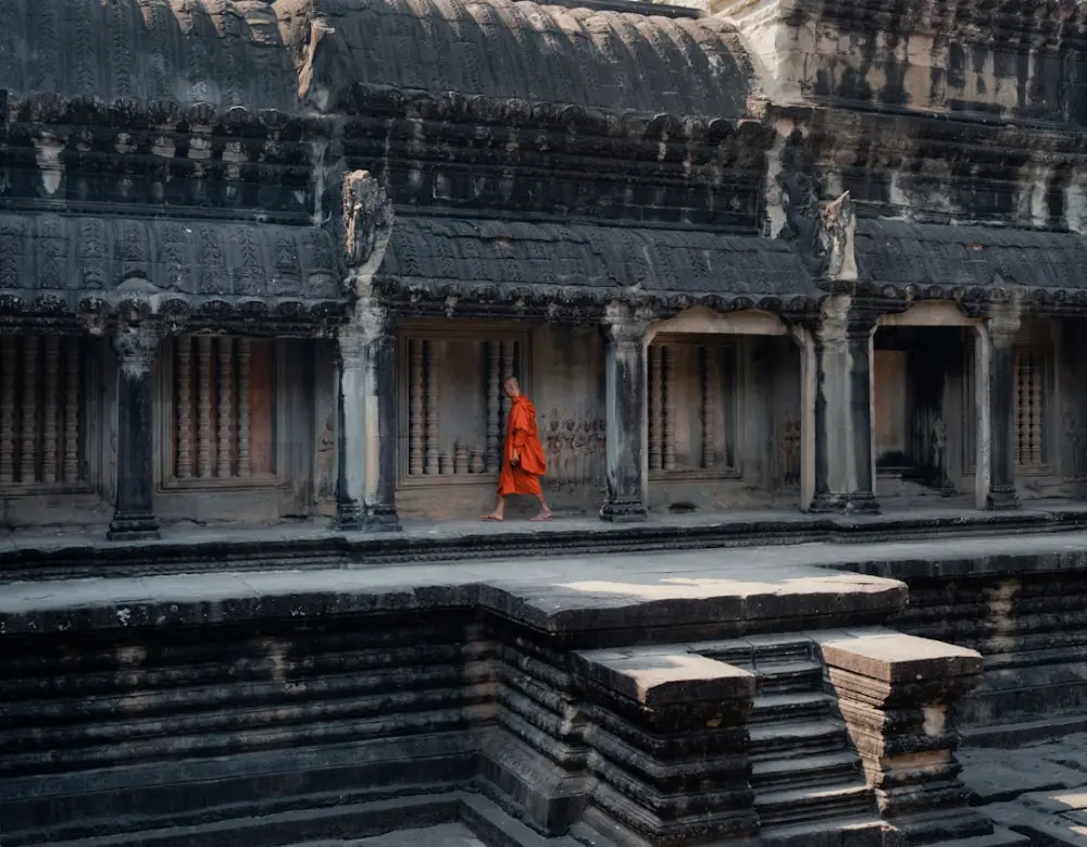 Orange-robed person walking ancient cambodian temple