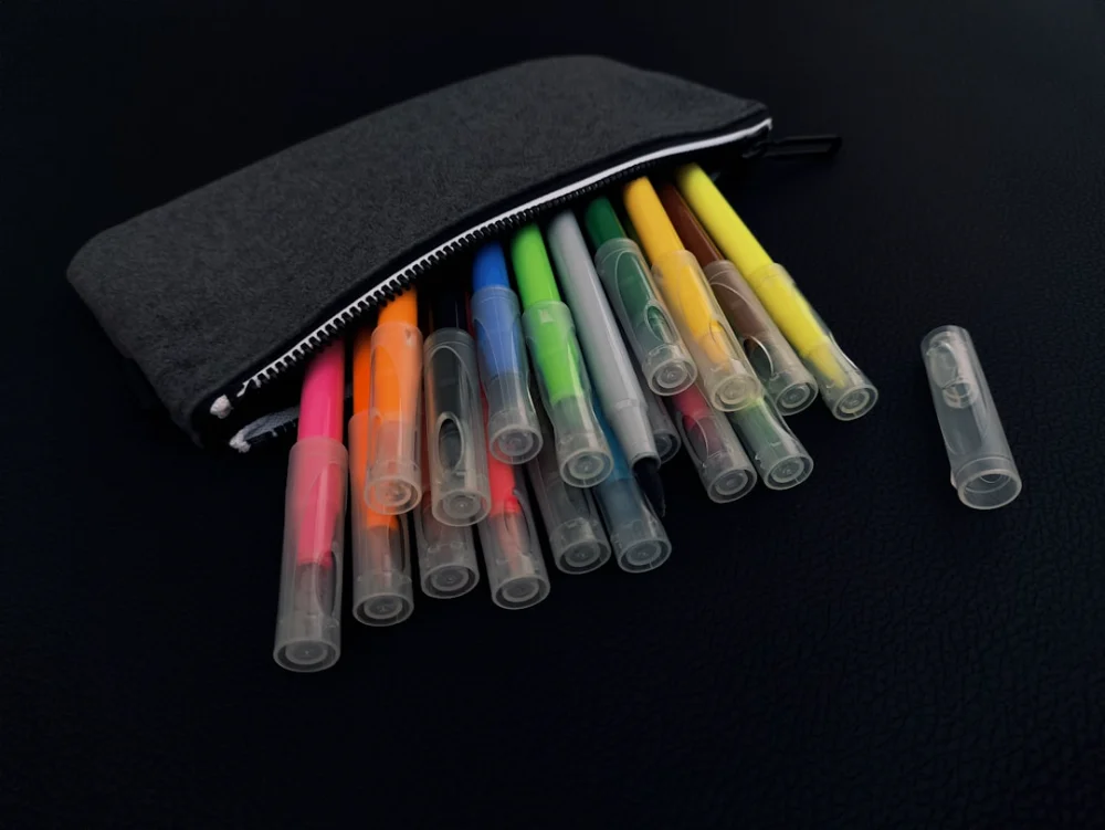 A pouch of markers and pens on a black surface