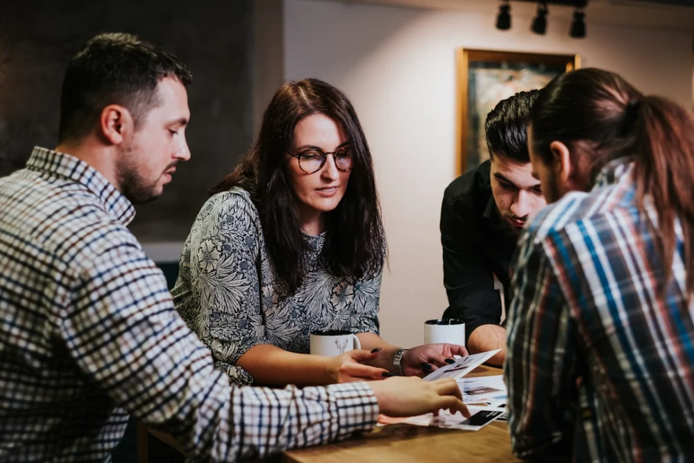 Four people reviewing documents at a wooden table in a workspace