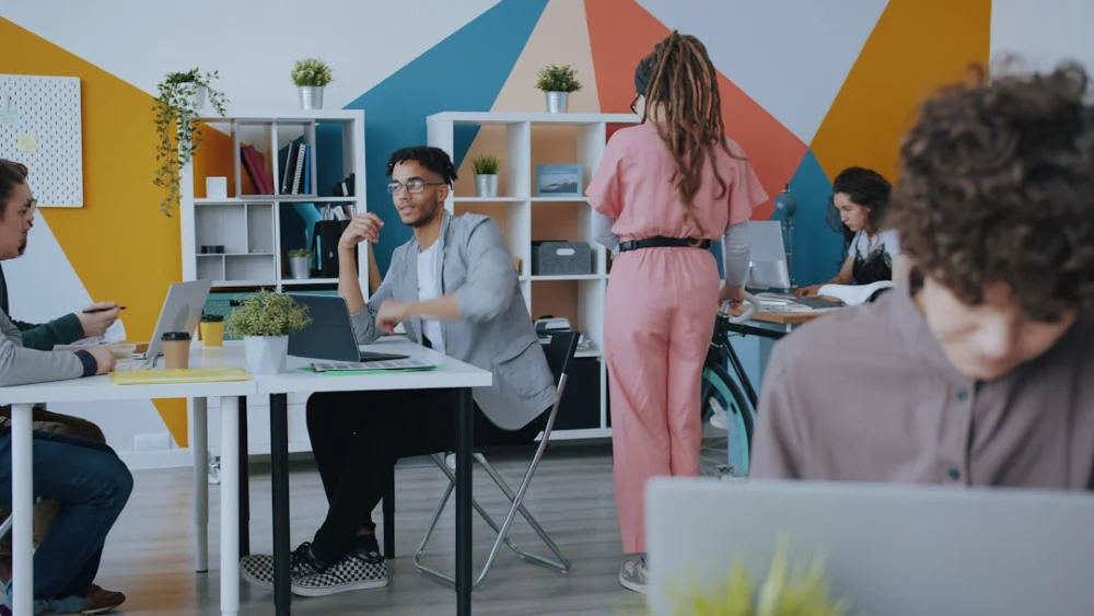 People working in a colorful office with geometric wall patterns and white shelving