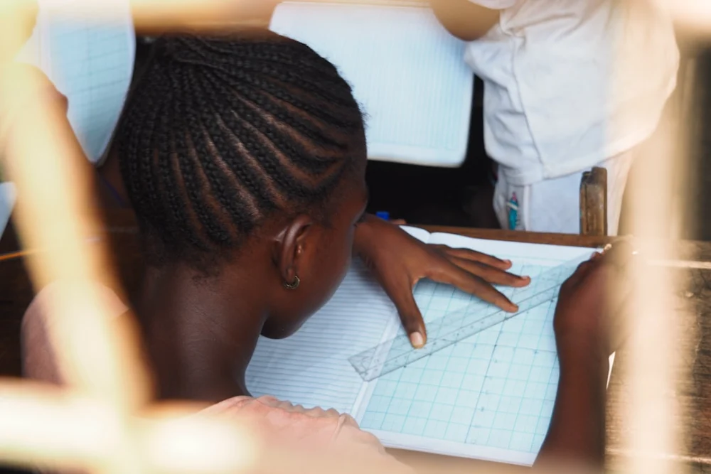 A student carefully draws lines with a ruler