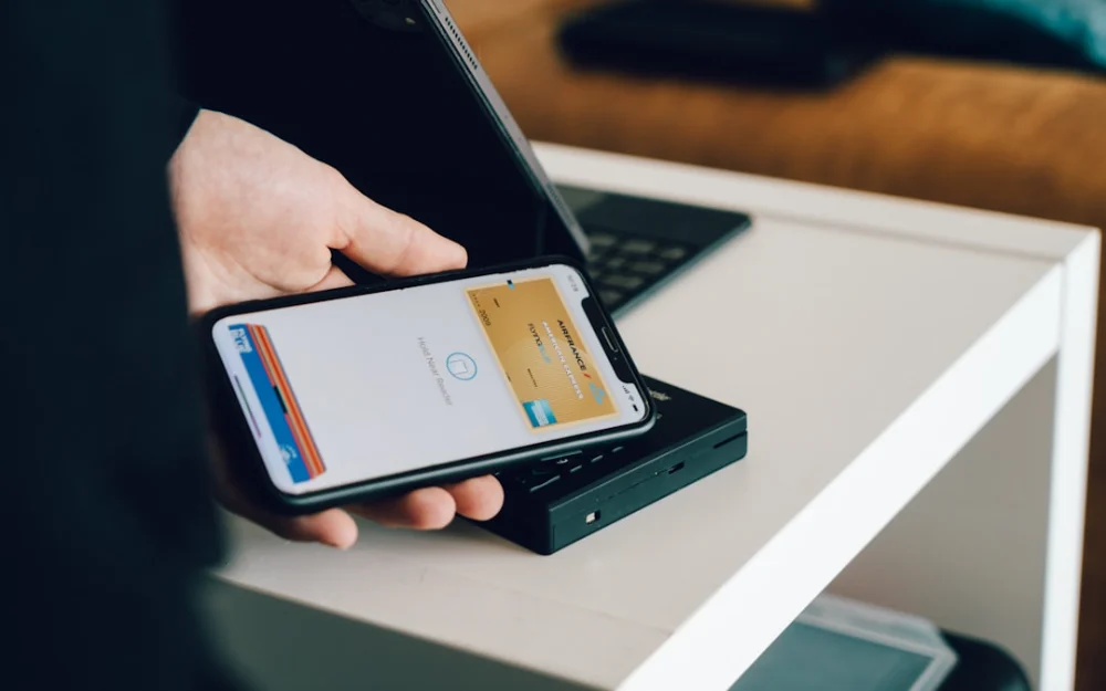 A person holding a smartphone over a card reader for contactless payment