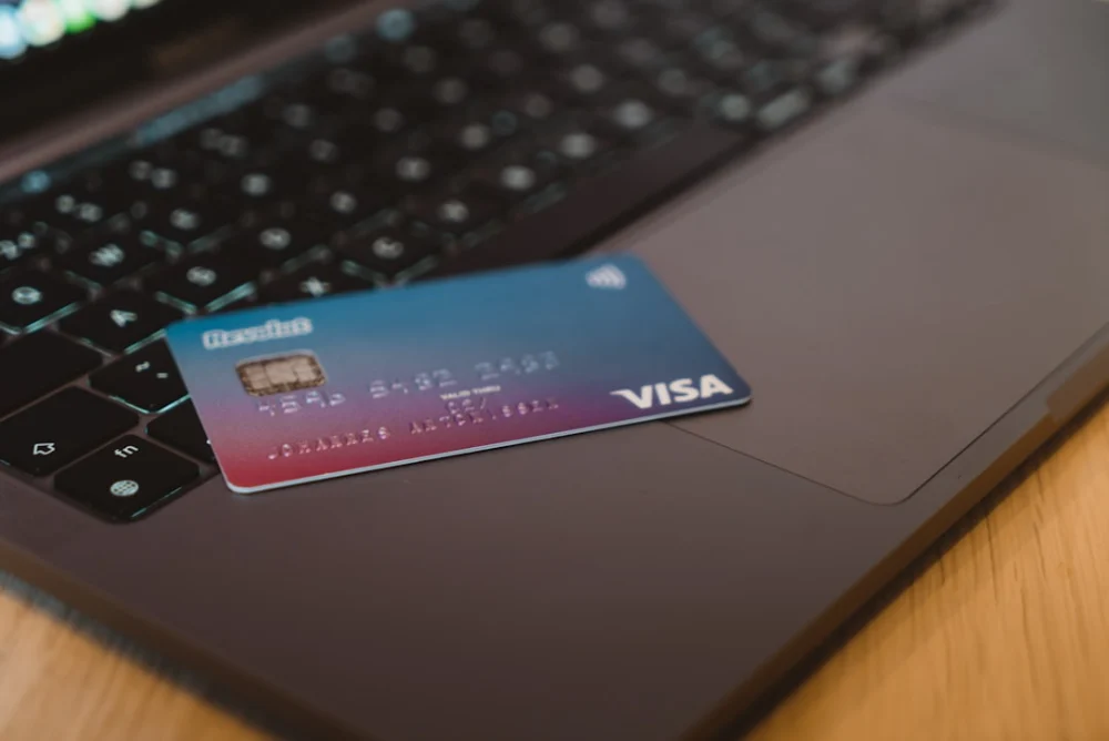 A blue and red gradient debit card resting on a dark laptop keyboard