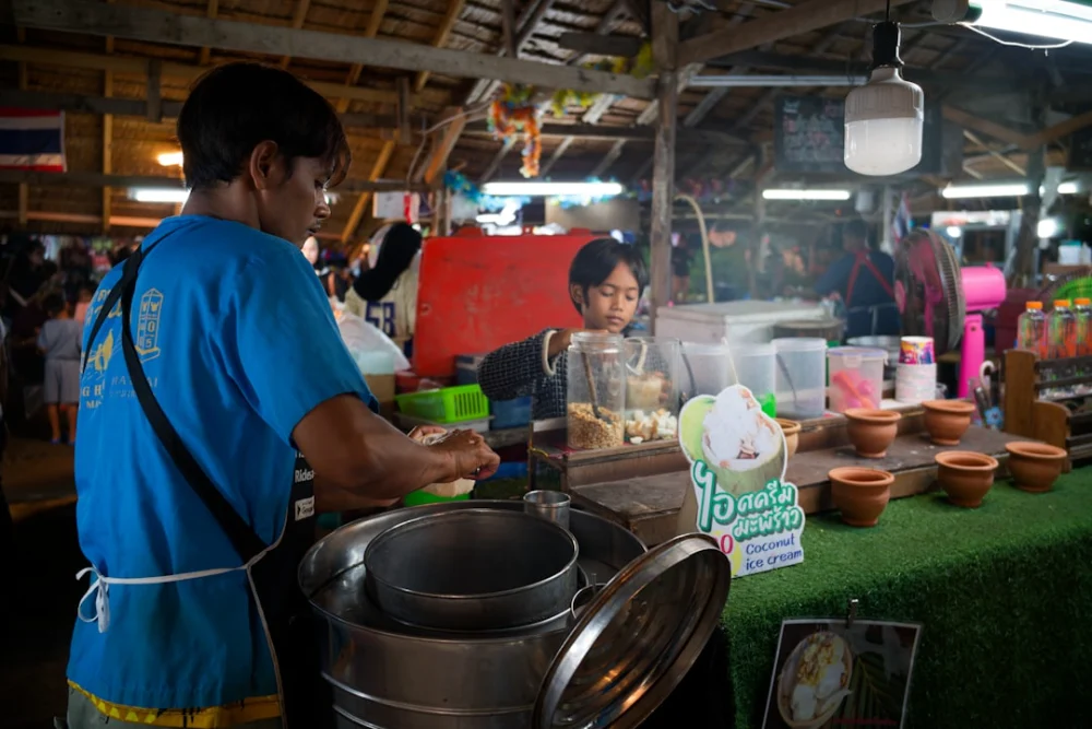 Vendor preparing food at a busy outdoor market stall