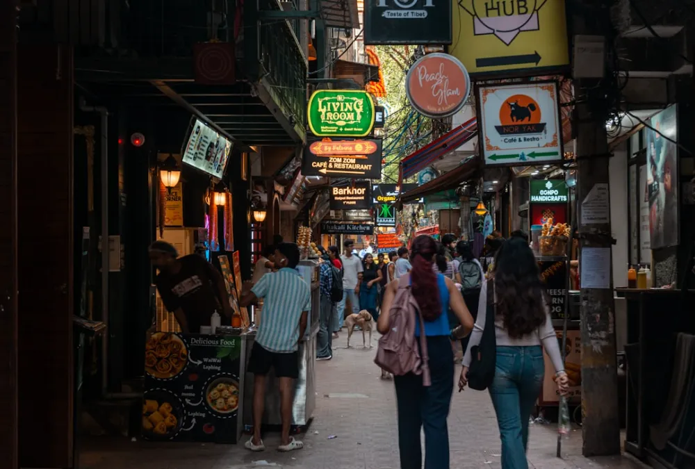 People walk down a narrow street with shops and signs