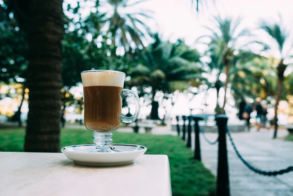 A glass of coffee with foam on a table