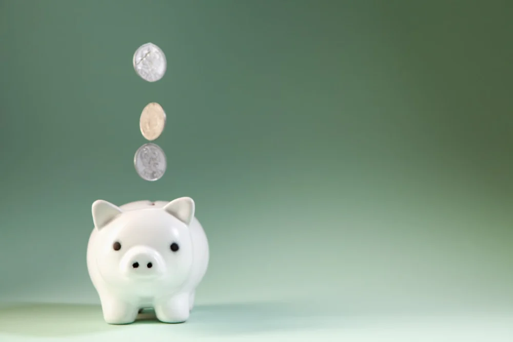 Coins falling into a white piggy bank