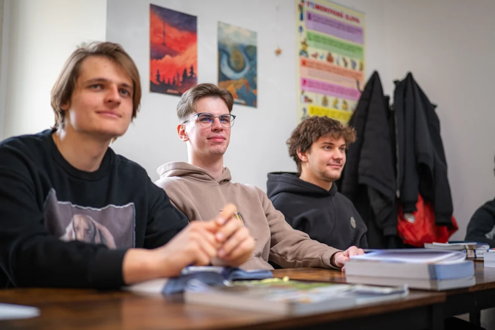 Three young men sitting at a table in a classroom