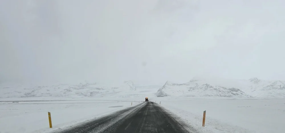 A lone figure on a snow-covered road towards mountains