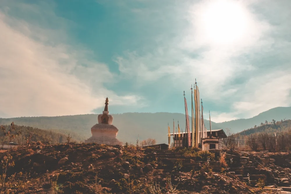 a church in the middle of a field with mountains in the background