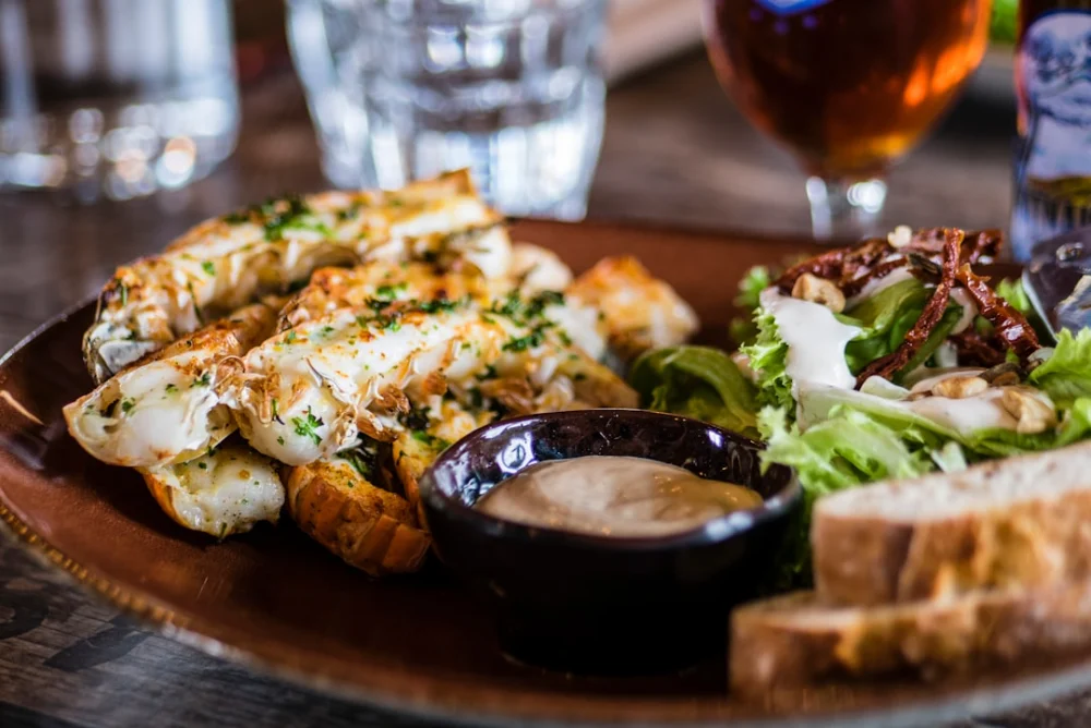 Grilled lobster tails with herbs beside a fresh salad and dipping sauce