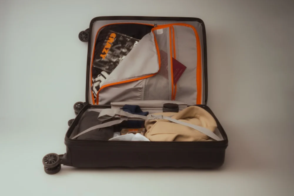 An open black suitcase packed with clothes and travel essentials