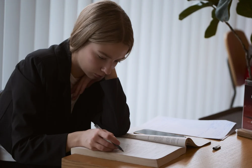 Young woman studying at a desk with an open book