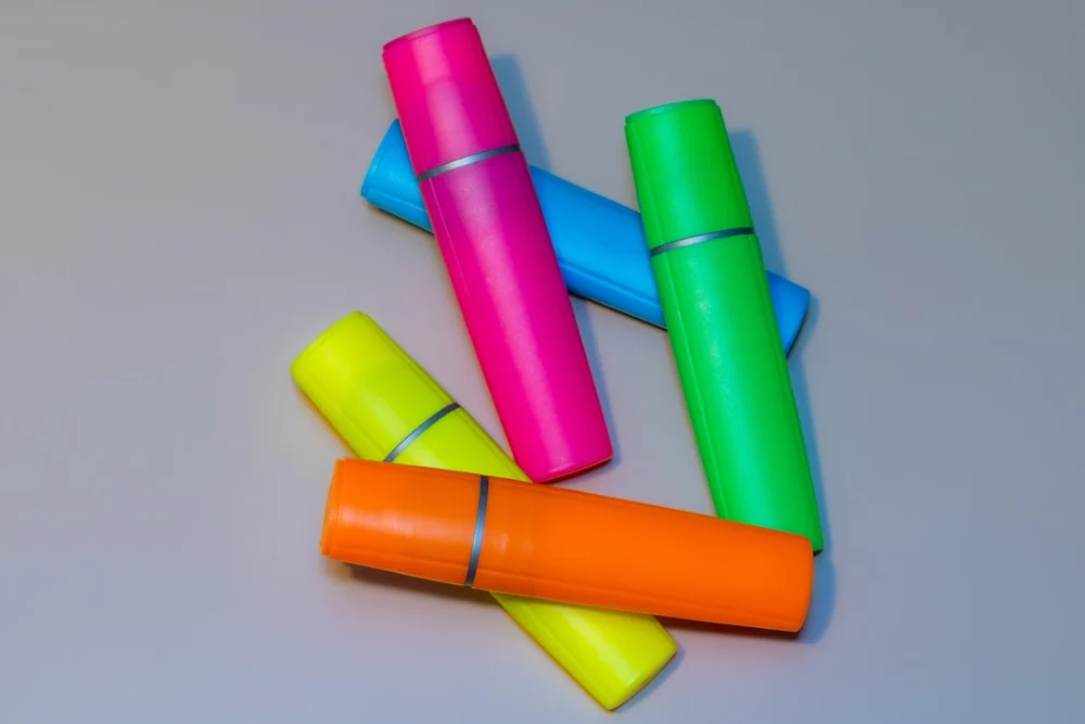 Several colorful highlighters scattered on a gray surface