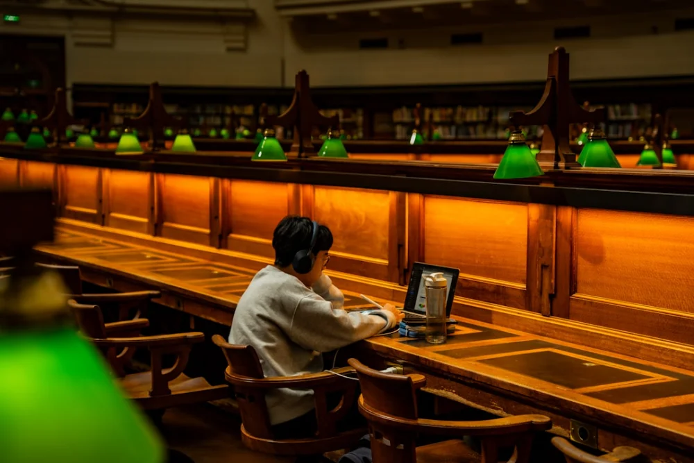 Person studying at a long wooden desk in library