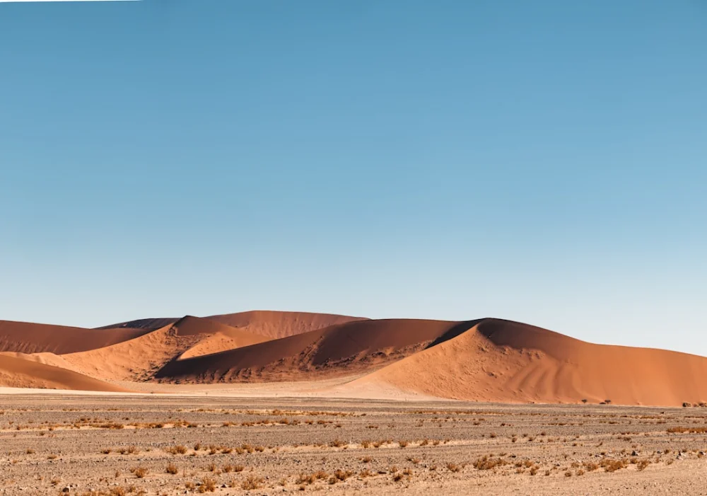 Vast orange sand dunes under a clear blue sky