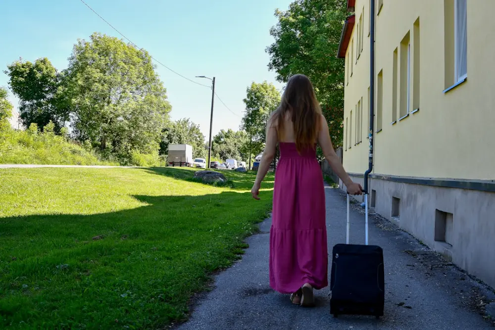 A woman in a pink dress pulls a suitcase outdoors