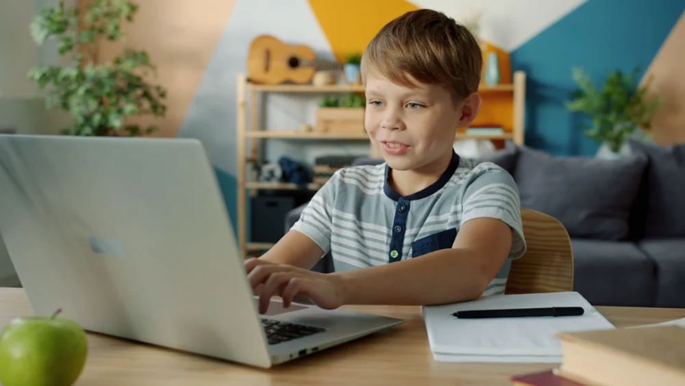Young boy learning on a laptop at a desk