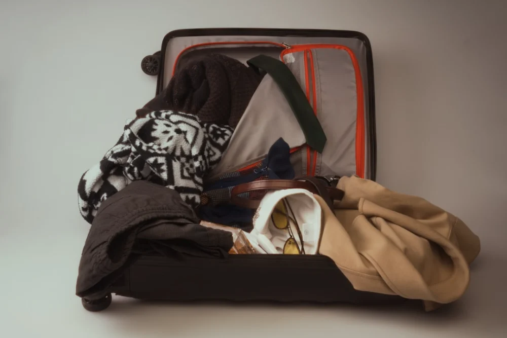 An open suitcase overflowing with various clothes
