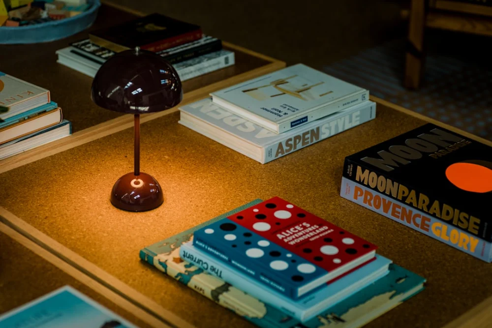 A small lamp illuminates books on a table