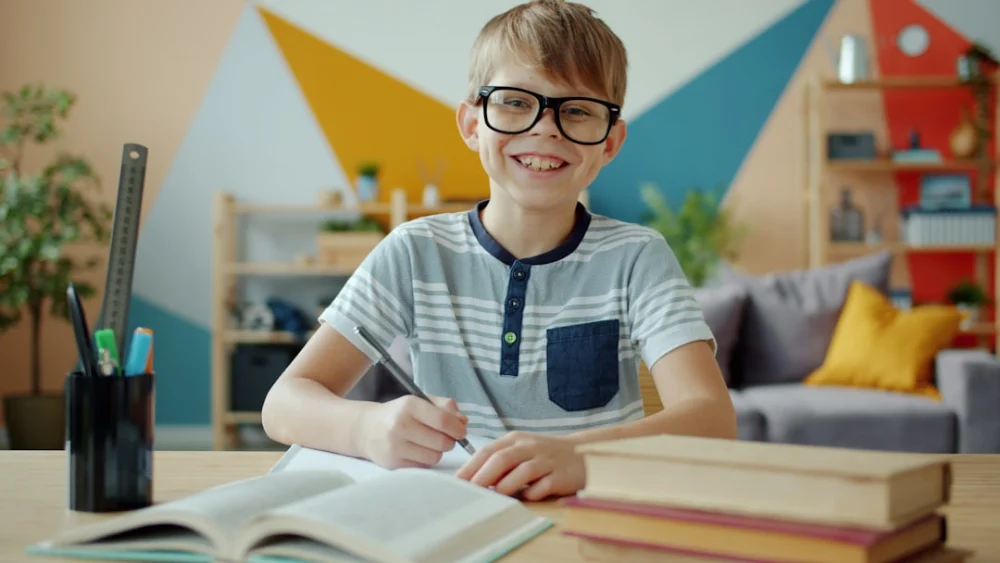 Smiling boy wearing glasses studying at a desk