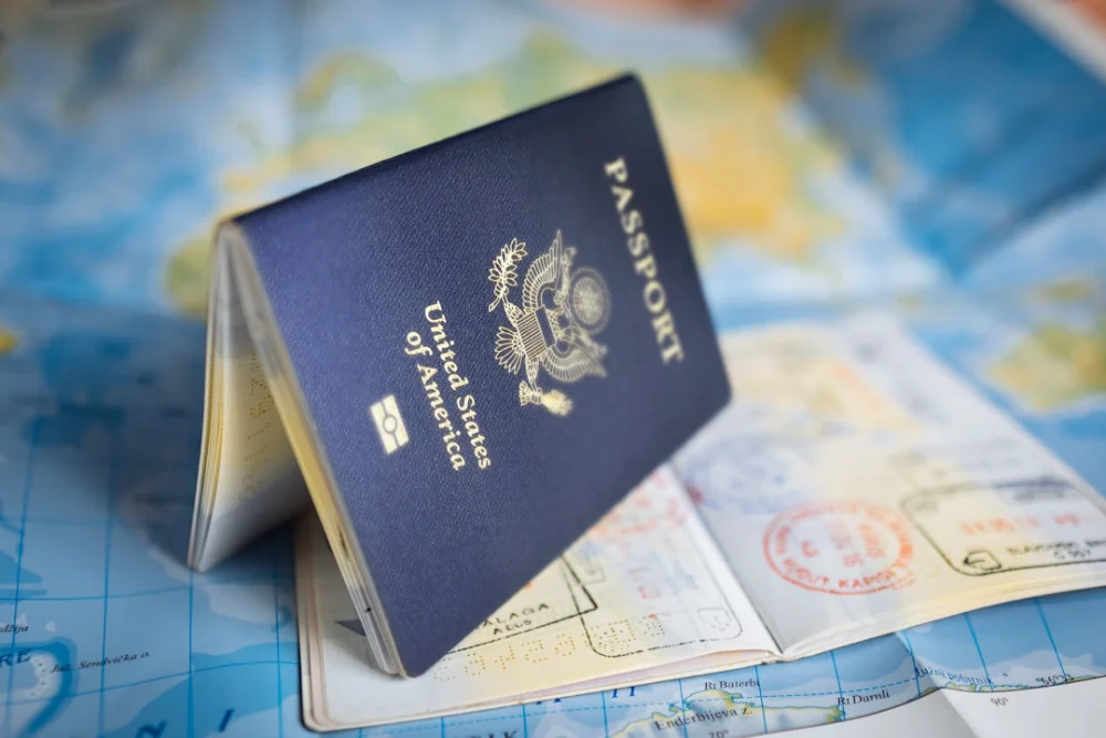 A United States passport resting open on a colorful world map