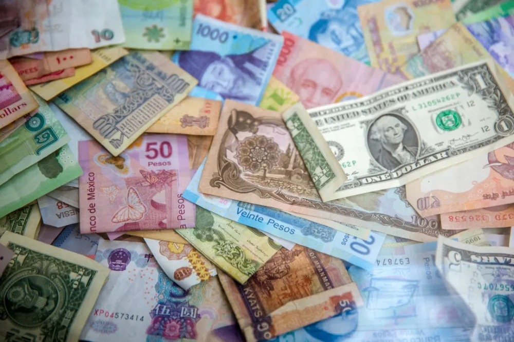 A collection of various international banknotes scattered across a flat surface