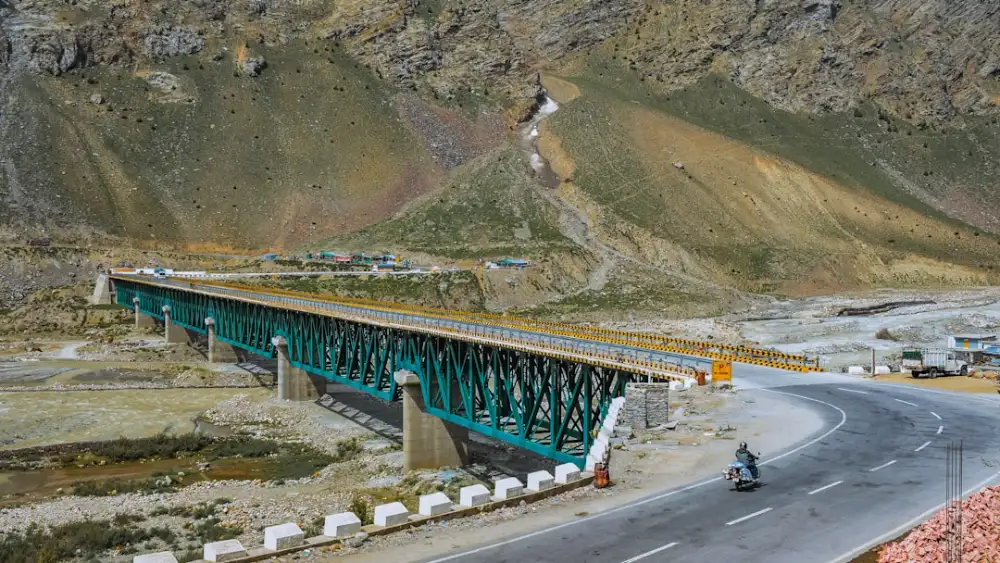 a motorcyclist rides across a bridge in the mountains