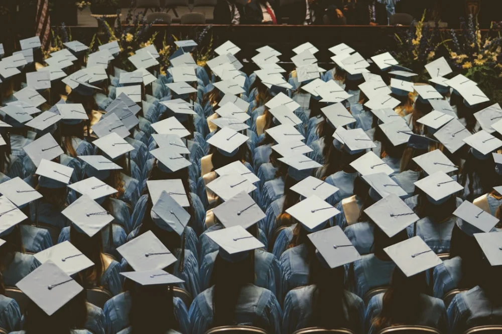 A large group of graduates in light blue gowns and caps at a ceremony