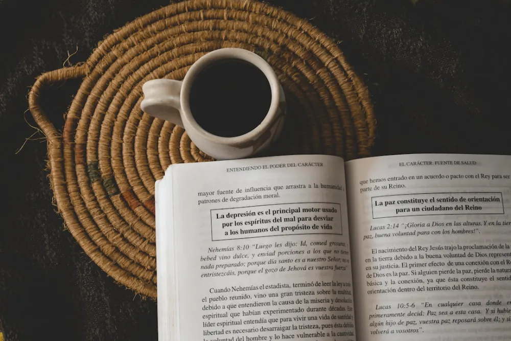 Coffee and a book lie on a woven mat